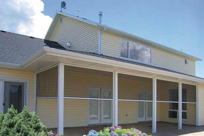 Back porch of a yellow home with multiple retractable screens lowered